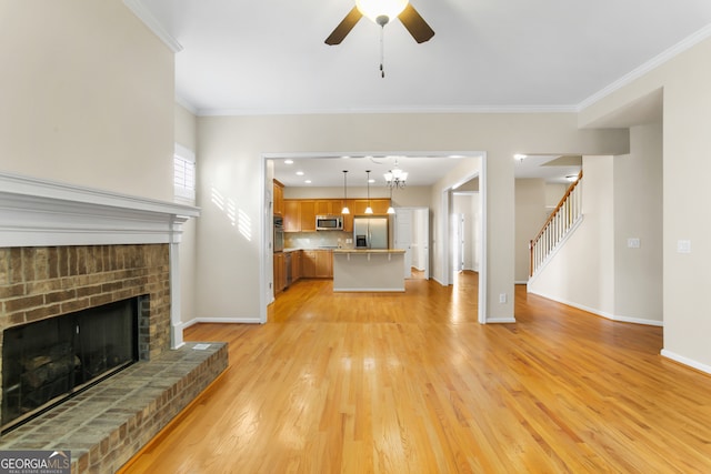 unfurnished living room with ceiling fan, light wood-type flooring, crown molding, and a brick fireplace