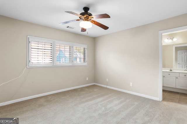 unfurnished bedroom with ensuite bath, ceiling fan, sink, and light carpet