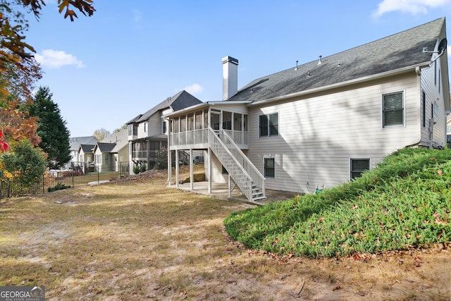 rear view of house featuring a sunroom and a yard