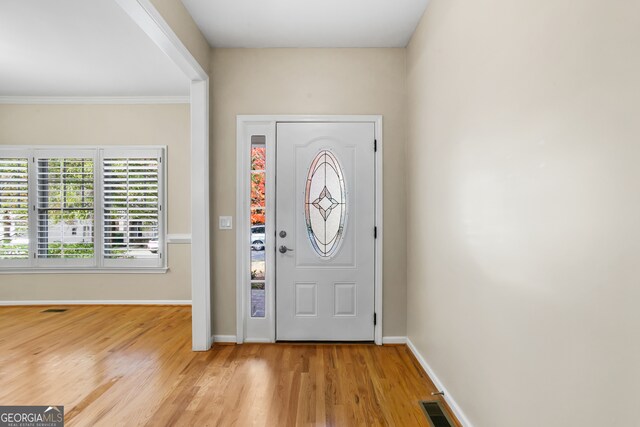 foyer featuring crown molding and light hardwood / wood-style flooring