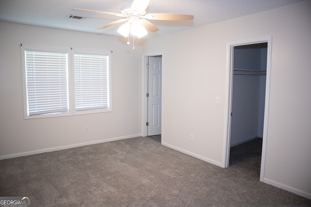 unfurnished bedroom with carpet, a walk in closet, a closet, and ceiling fan