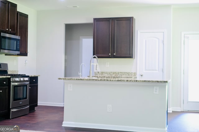 kitchen featuring light stone countertops, dark brown cabinets, dark hardwood / wood-style flooring, and stainless steel appliances