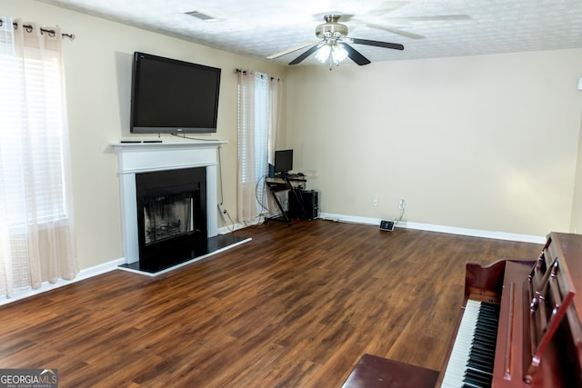 unfurnished living room featuring a textured ceiling, ceiling fan, and dark wood-type flooring