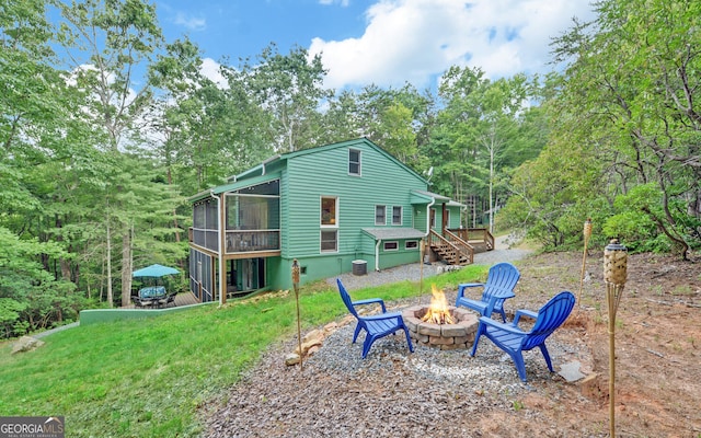 rear view of property with an outdoor fire pit and a sunroom