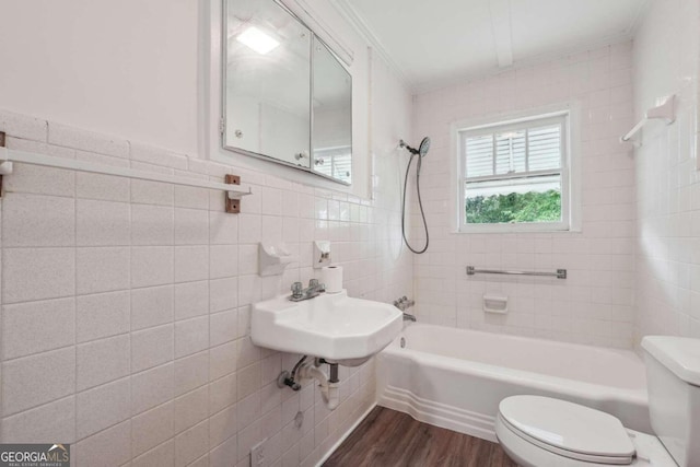 full bathroom featuring tiled shower / bath combo, sink, hardwood / wood-style flooring, tile walls, and toilet