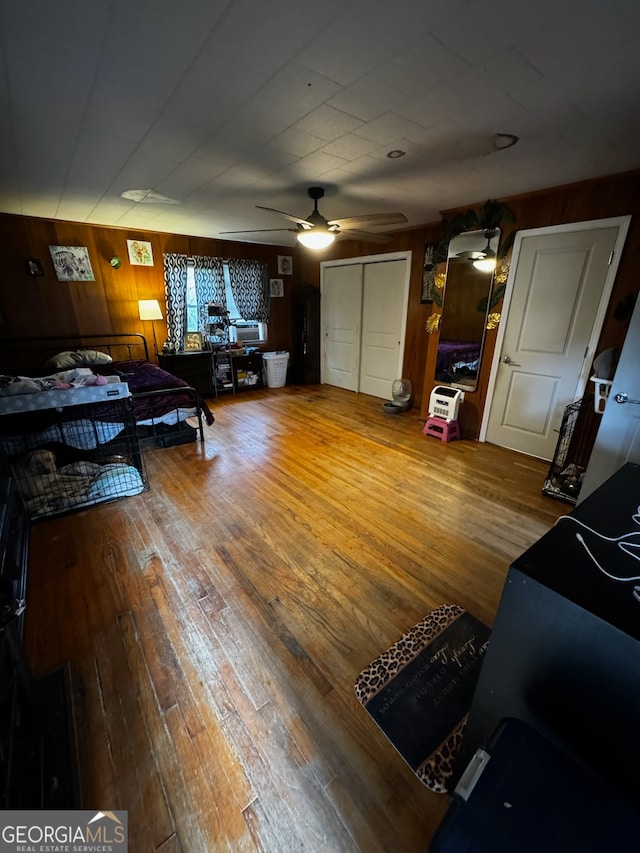 living room with ceiling fan, wooden walls, and wood-type flooring