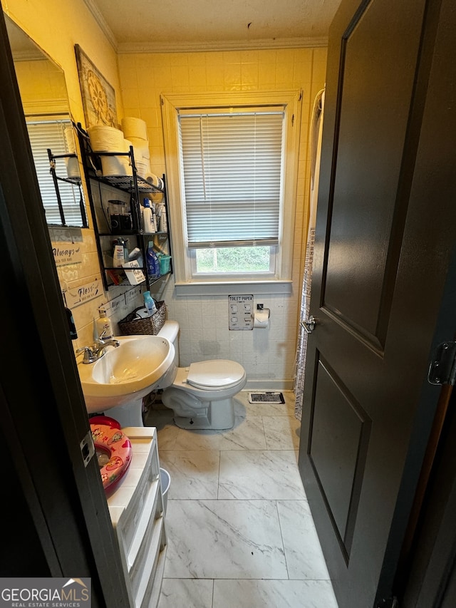 bathroom with crown molding, sink, tile walls, and toilet