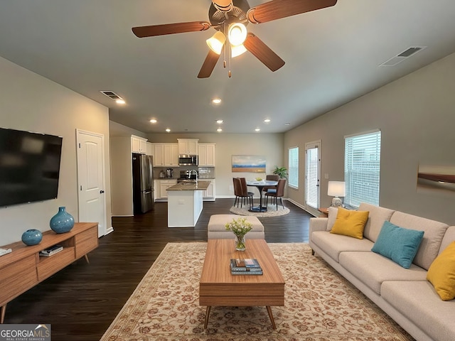 living room featuring ceiling fan, dark wood-type flooring, and sink