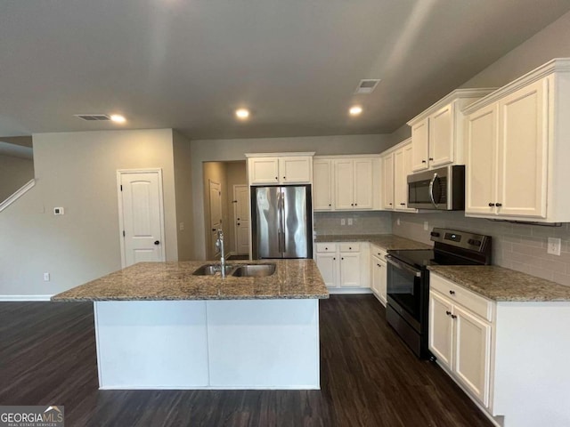 kitchen with a kitchen island with sink, stainless steel appliances, dark wood-type flooring, sink, and white cabinetry