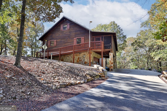 view of home's exterior featuring a sunroom, a garage, and a wooden deck