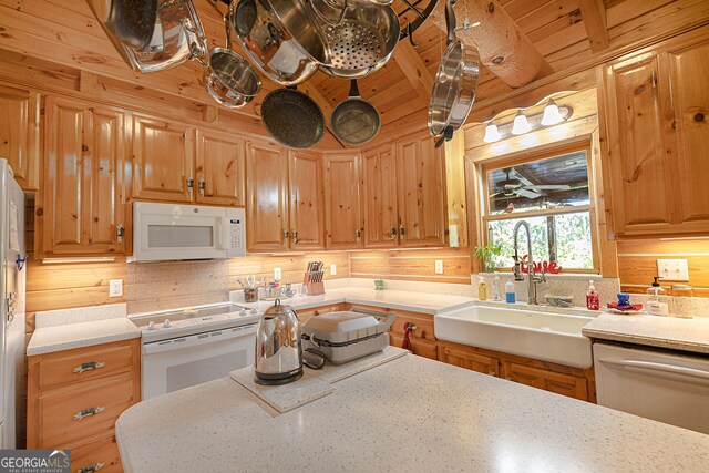 kitchen with backsplash, wooden walls, sink, and white appliances