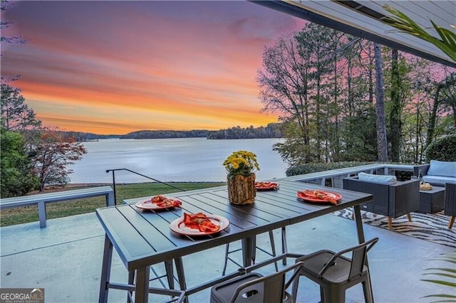 balcony at dusk with a patio, a water view, and outdoor lounge area