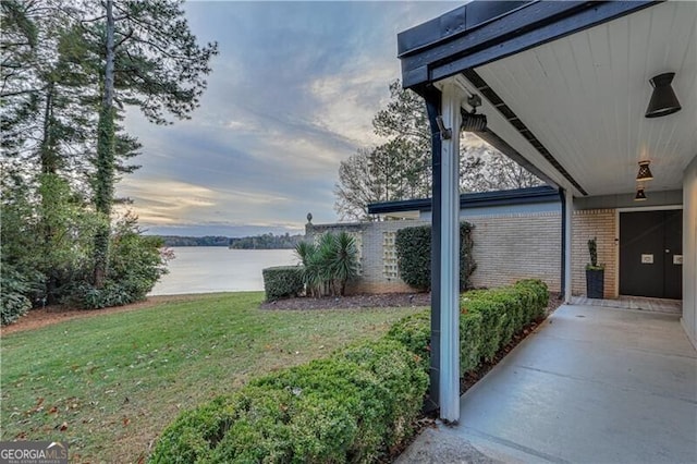 yard at dusk with a water view and a patio area