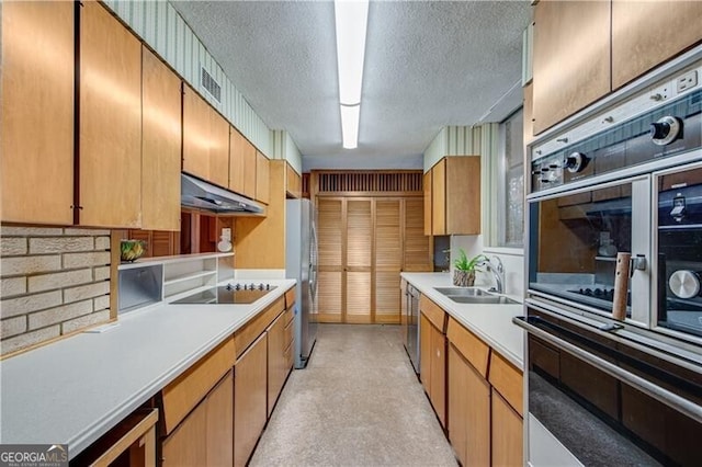 kitchen featuring stainless steel appliances, beverage cooler, sink, and a textured ceiling