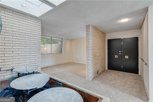 carpeted entrance foyer featuring a textured ceiling and a skylight