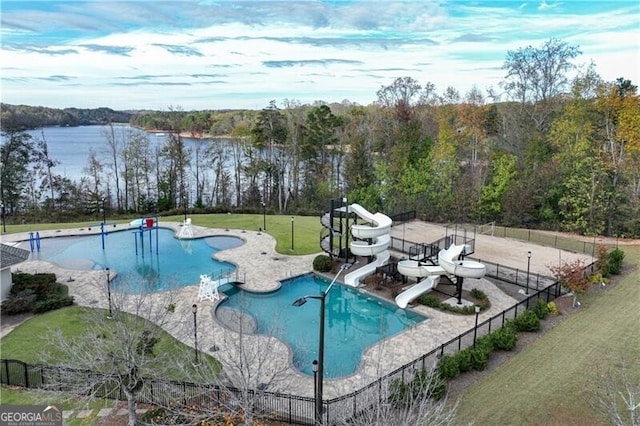 view of swimming pool featuring a water view, a water slide, a patio area, and a lawn