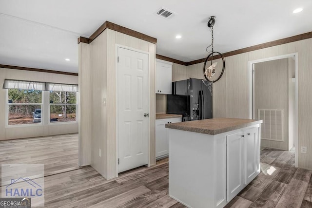 kitchen featuring black refrigerator, white cabinets, hanging light fixtures, and a kitchen island