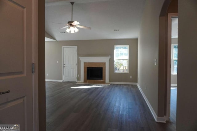 unfurnished living room featuring dark hardwood / wood-style flooring, vaulted ceiling, and ceiling fan