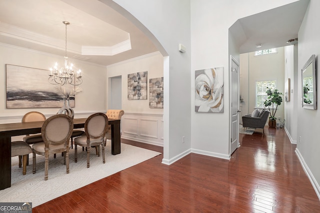 dining room with ornamental molding, a tray ceiling, dark wood-type flooring, and a notable chandelier