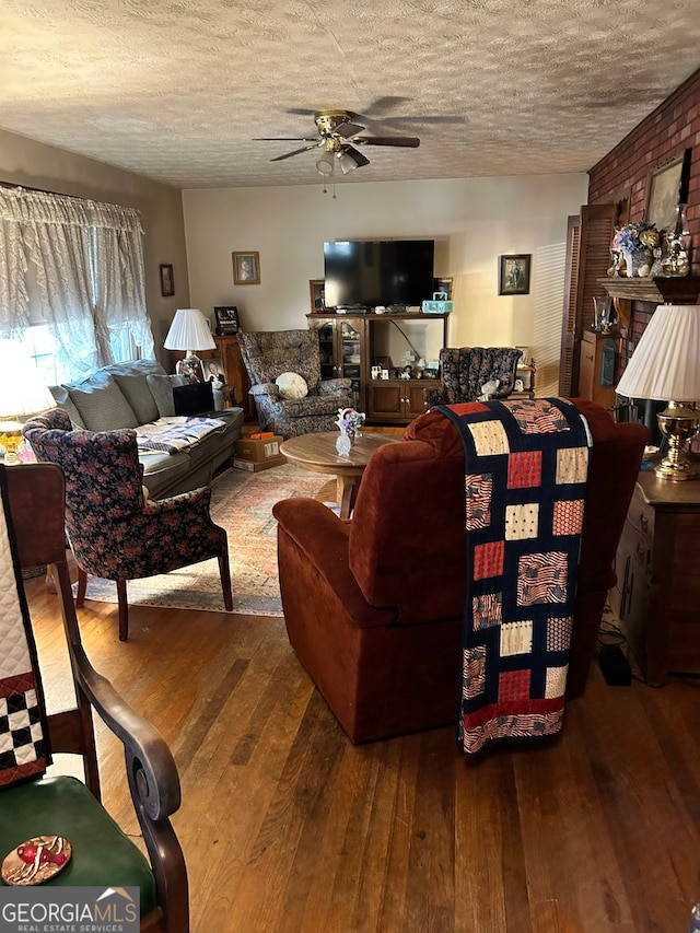 living room featuring hardwood / wood-style floors, ceiling fan, and a textured ceiling