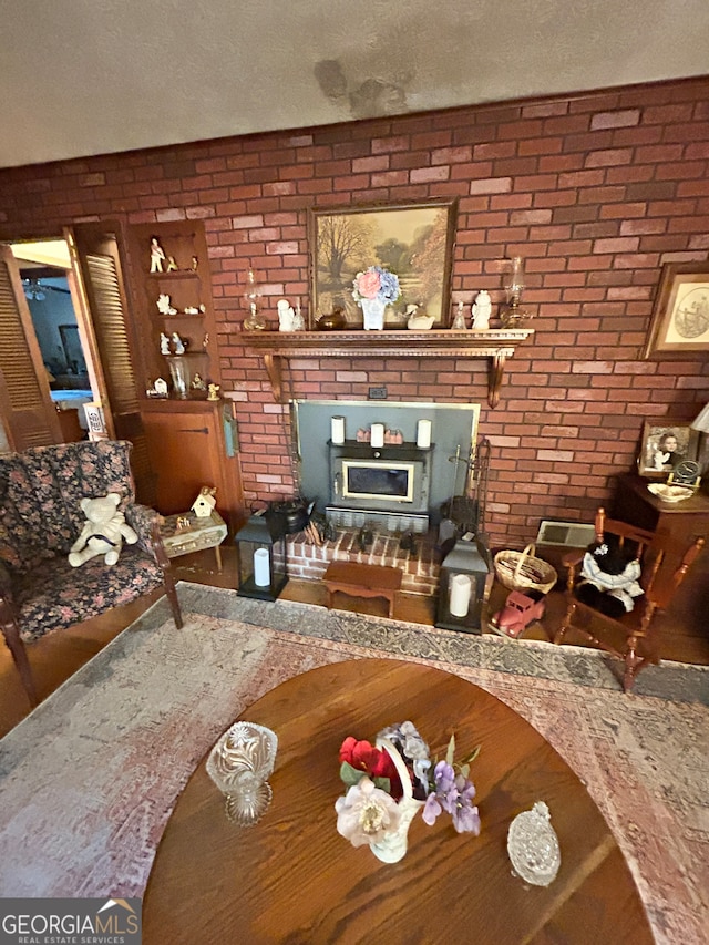 unfurnished living room featuring a textured ceiling, a fireplace, and brick wall