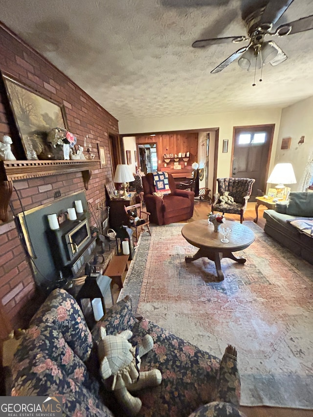 living room featuring ceiling fan, a textured ceiling, and brick wall