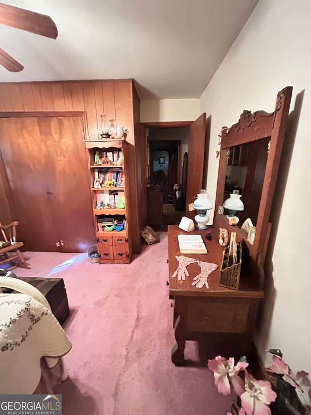 interior space with ceiling fan and wooden walls