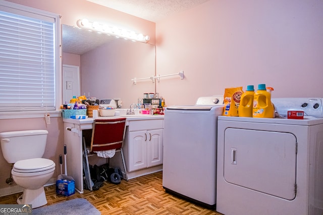 laundry room with separate washer and dryer, light parquet floors, and a textured ceiling