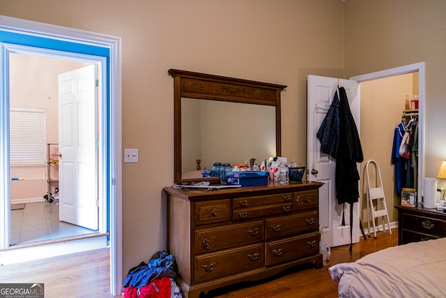 bedroom featuring a walk in closet, light wood-type flooring, and a closet