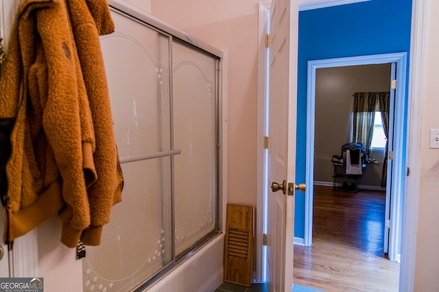 bathroom with combined bath / shower with glass door and hardwood / wood-style flooring