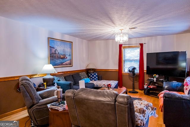 living room featuring a textured ceiling, hardwood / wood-style flooring, and an inviting chandelier