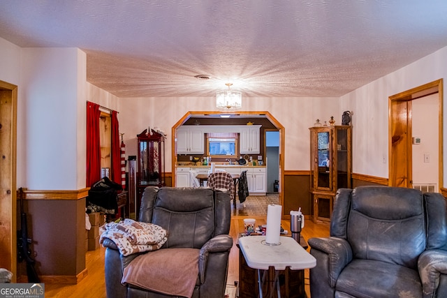 living room featuring a chandelier, a textured ceiling, and light hardwood / wood-style floors