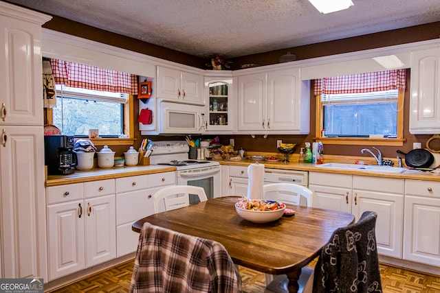 kitchen featuring sink, parquet flooring, a textured ceiling, white appliances, and white cabinets