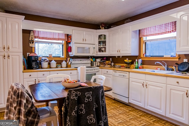 kitchen featuring sink, light parquet floors, a textured ceiling, white appliances, and white cabinets