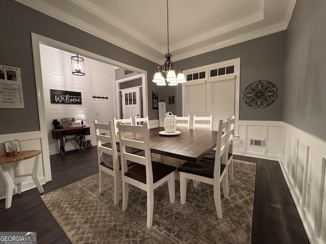 dining space with a tray ceiling, dark hardwood / wood-style flooring, a chandelier, and ornamental molding