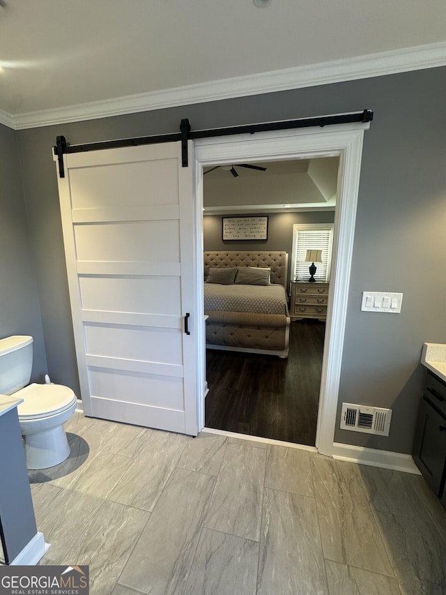 bathroom with crown molding, vanity, wood-type flooring, and toilet