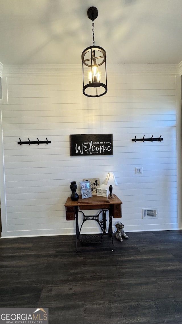 mudroom featuring wood walls, dark hardwood / wood-style flooring, and an inviting chandelier