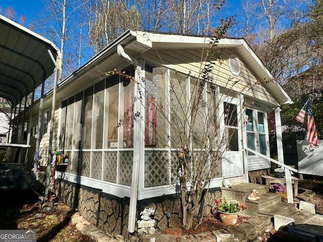 view of home's exterior with a carport and a sunroom