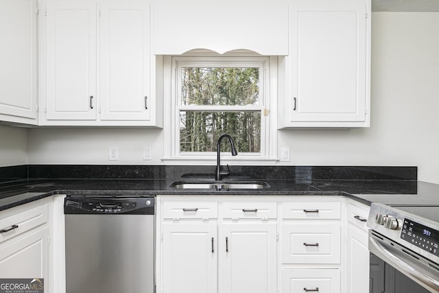 kitchen with stainless steel appliances, dark stone countertops, white cabinets, and sink