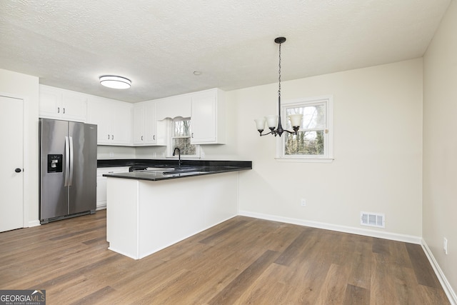 kitchen with stainless steel refrigerator with ice dispenser, white cabinets, hanging light fixtures, and kitchen peninsula