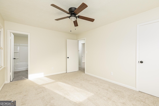 unfurnished bedroom featuring connected bathroom, a textured ceiling, ceiling fan, and light colored carpet