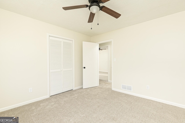 unfurnished bedroom with ceiling fan, light colored carpet, and a closet