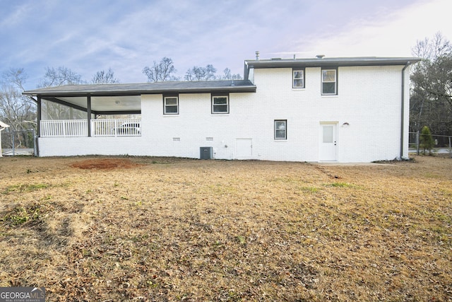 back of house with central air condition unit and a yard