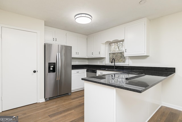 kitchen featuring stainless steel appliances, kitchen peninsula, dark wood-type flooring, sink, and white cabinetry