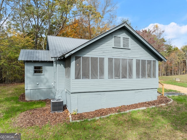 view of property exterior featuring a sunroom, a yard, and central AC unit