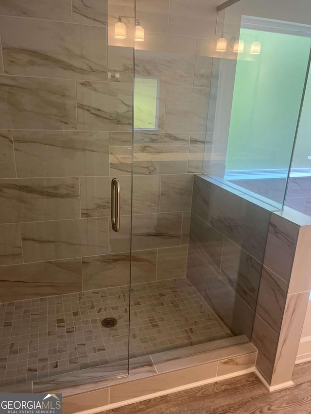 bathroom with hardwood / wood-style floors and an enclosed shower