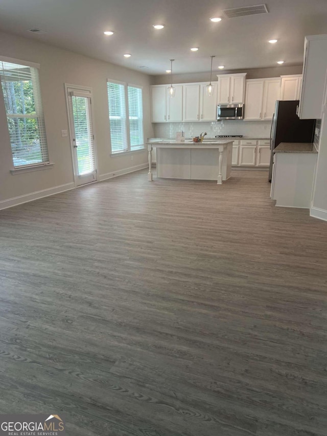 kitchen with a breakfast bar, a kitchen island with sink, decorative light fixtures, dark hardwood / wood-style floors, and white cabinetry