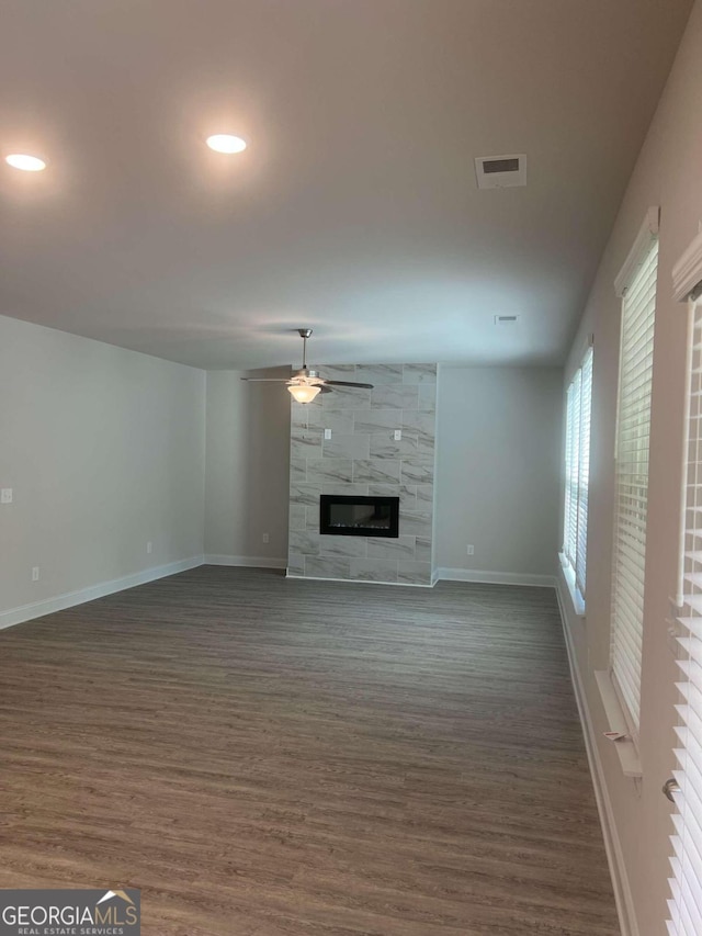 unfurnished living room featuring a fireplace, dark hardwood / wood-style flooring, and ceiling fan