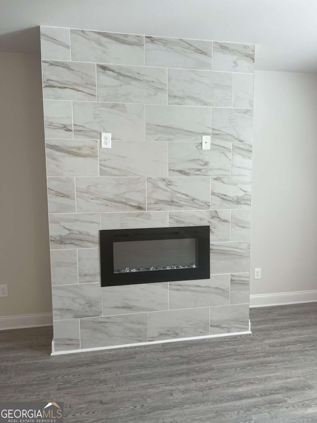 interior details with wood-type flooring and a tiled fireplace