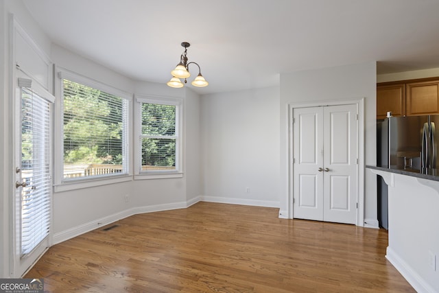 unfurnished dining area featuring an inviting chandelier and hardwood / wood-style flooring